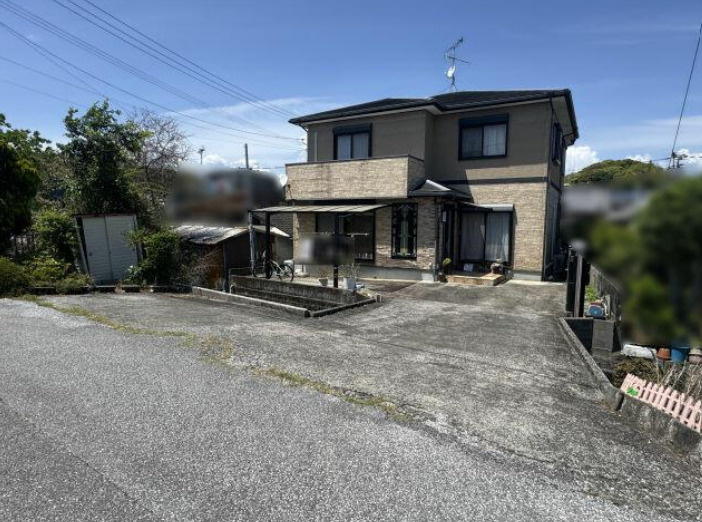 「小学校近くの6LDK」高知市長浜　中古一戸建ての前面道路含む現地写真|落ち着いた色合いと石目調の外壁が印象的な住まい。屋根付きテラスと2階バルコニーを備えています。