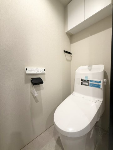 双秀ビルのトイレ|清潔感のあるホワイトを基調としたトイレ。温水洗浄便座を備え、上部には収納棚も設けられた使い勝手の良い空間です。