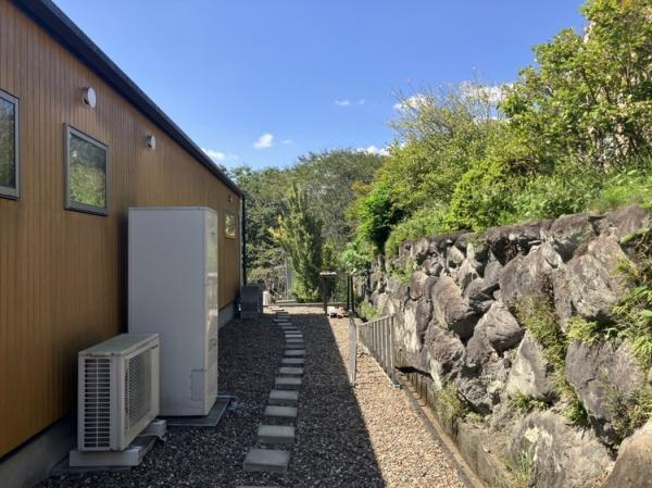 三重町　戸建てのその他|建物の側面には小窓が並び外壁の木目調が上品な雰囲気です。石垣と豊かな緑が調和し周囲には自然の景観が広がります。