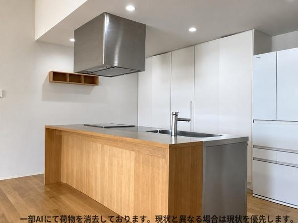 三重町　戸建てのキッチン|木目調のカウンターが印象的なキッチンです。収納スペースが豊富に設けられています。シンプルなデザインですっきりとした印象です。アイランド型で動線も確保されています。清潔感のある空間です。