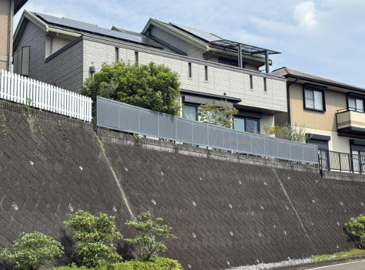 「ルーフバルコニー＆エレベーターのある4SLDK」高知市春野町南ヶ丘６丁目　中古一戸建ての前面道路含む現地写真|高低差のある敷地に建つ2階建て住宅。横に広がるバルコニーが印象的な外観です。