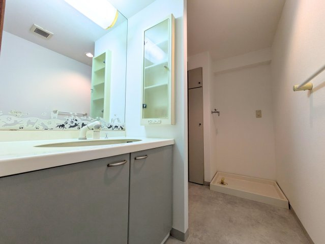 サンクレスタ緑町の洗面所|ワイドな鏡を備えた洗面台と壁面棚を設置し、朝の身支度や洗濯の動線もスムーズに行えます。