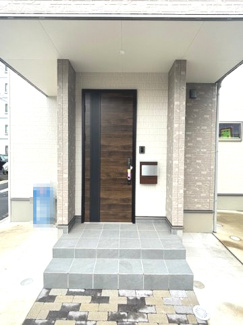 【玄関】 | 安佐南区川内2丁目（角地）【新築未入居】 | シックな木目調のドアが印象的な玄関アプローチです。大きな屋根庇（ひさし）が突き出たデザインとなっており、雨の日でも濡れにくく快適に出入りできます。