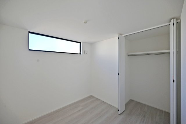 宝塚市中州2丁目新築一戸建て│3LDK+駐車1台可の洋室|高い位置に設けた横長の窓から、やわらかな光が入る洋室。白い壁と淡い木目の床が、すっきりとした印象です。折れ戸付きのクローゼットには洋服を掛けて収納できます。