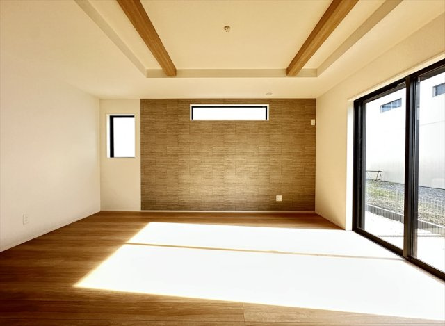 【居間・リビング】 | 新座市野火止3丁目　新築一戸建住宅　全61棟　(志木本店) | アクセントクロスが印象的なリビング。折上げ天井の化粧梁が空間に立体感をもたらし、明るい陽光が差し込む開放的な空間です。