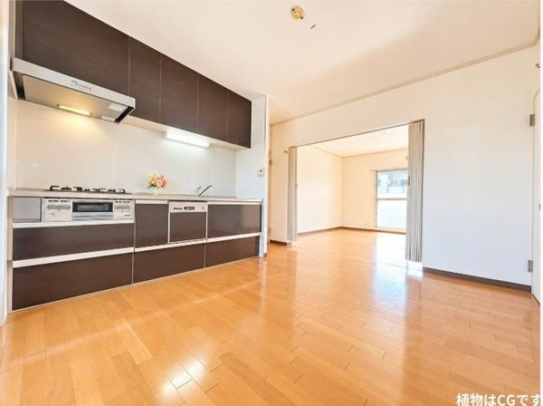 藤阪パークハイツ　１号棟　中古 マンションのキッチン|隣接する洋室とつながる開放的なダイニングキッチン。美しい木目のフローリングとシックなキッチンが調和し、家族の成長やライフスタイルに合わせて、のびのびと暮らせる魅力的な空間です。