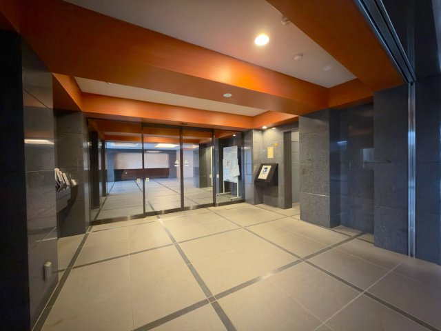 コスモシティ朝霞台のエントランス|上品な照明設計と石調タイルが洗練された印象を与えるエントランスロビーです。清掃が行き届いた清潔感ある空間が広がり、居住者様や来訪者を温かく迎え入れます。日勤管理体制で維持管理も良好です。