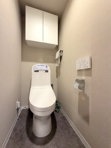 コスモシティ朝霞台のトイレ|清潔感のある温水洗浄便座付きトイレです。手洗い付きタンクやトイレットペーパー等のストックに重宝する上部吊戸棚を備えており、いつでもすっきりと快適な空間をキープ。毎日心地よくご利用いただけます。