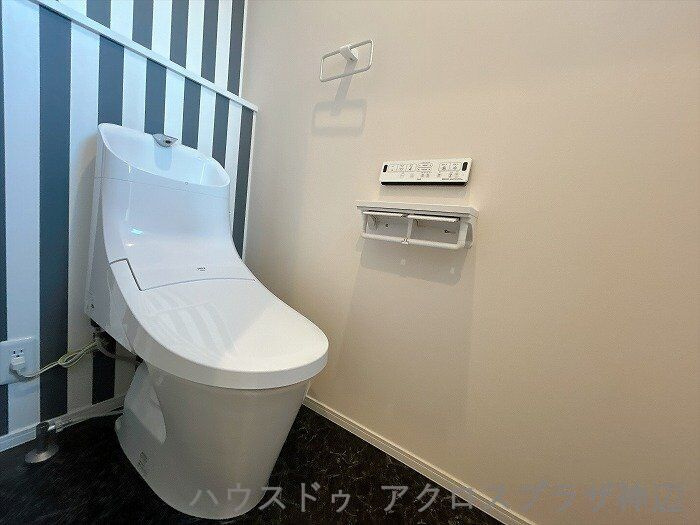 北吉津町3丁目のトイレ|【トイレ】シックなダークトーンの床と遊び心あるアクセントクロスでおしゃれに仕上げた空間。