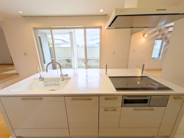 北土居5丁目戸建てのキッチン|アイランド型の対面キッチン。フラットな調理台と引き出し収納を備えています。