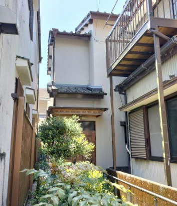 高知市赤石町の売地の周辺|敷地奥には既存建物があり、植栽が見られます。