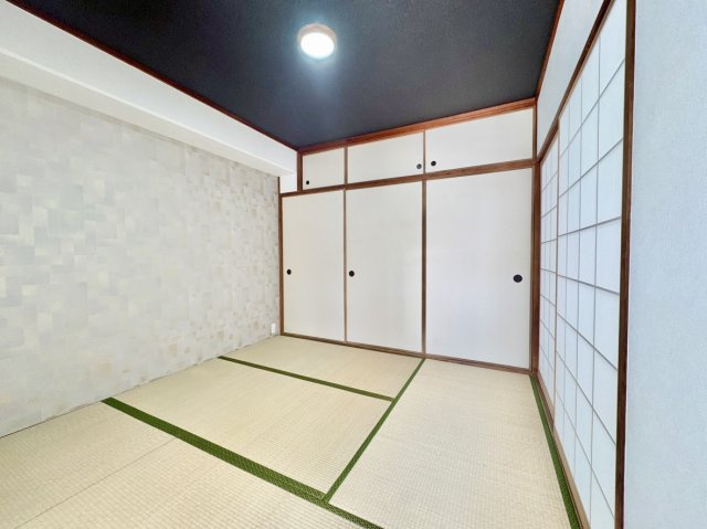 荒神山マンションの和室|黒天井とアクセントクロスが目を惹く和モダンな約4.5帖の和室。天袋付きの大容量押し入れを完備し、お布団や荷物をすっきり収納できます。畳の温かみと高いデザイン性を兼ね備えた、心地よい空間です。