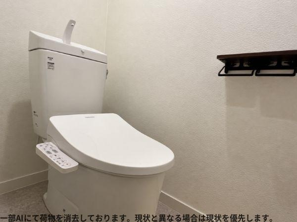 ビオス羽田のトイレ|シンプルで清潔感のあるトイレ空間です。操作パネル付きの便座が設置されています。壁面にはペーパーホルダーと小棚があり使いやすいレイアウトです。床や壁も落ち着いた色合いでまとめられています。