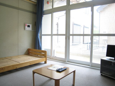 【居間・リビング】 | ボヌールＭ | 木製ベッド、ローテーブル、TV、カーテン。じゅうたん敷きです。