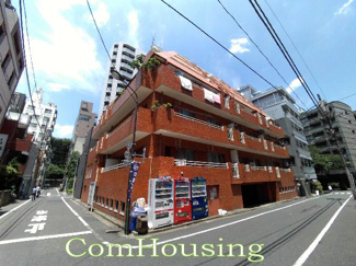 【外観】 | 茶色のタイル貼りの外観。道路奥の向こう側には靖国神社の緑が見えます。