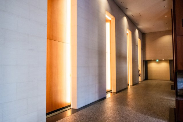 【エントランス】 | 【マスターズコリドール】木製パネルとライムストーンがリズミカルに配置され、アプローチの高揚感を演出。
