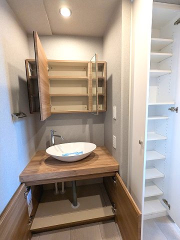 RESIDIA町屋の設備|トイレと独立した洗面室、室内廊下とキッチンからの2WAYです、三面鏡付独立洗面台、大型の収納付、収納向かいに洗濯機置場、排水口のお手入れしやすい様に手前中央に配置し、足高の防水パンです