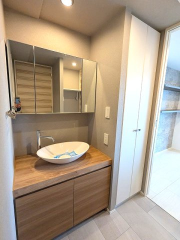 RESIDIA町屋の洗面所|トイレと独立した洗面室、室内廊下とキッチンからの2WAYです、三面鏡付独立洗面台、大型の収納付、収納向かいに洗濯機置場、排水口のお手入れしやすい様に手前中央に配置し、足高の防水パンです