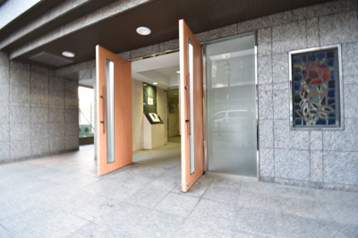 【エントランス】 | ルピナス国立ステーションスクエア　マンション | 大理石調の外壁に、温かさというエッセンスを加えた木目調のドア。住まう人を優しく迎え入れます。
