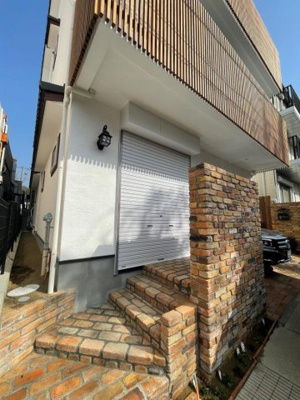 【外観】 | プレタメゾン芦屋岩園 | スイス漆喰の外壁に、イペ材、アンティークレンガのアプローチ、こだわりの街灯。アンティークレンガの外壁前（道路側に）には季節の花や樹木を植栽しております。船舶照明が優しく外観を照らします。