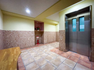 【エントランス】 | エレベーターの前には腰掛け用のベンチがあります。