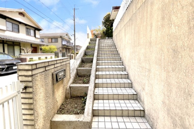 【外観】 | 亀岡市南つつじヶ丘大葉台一丁目　中古戸建 | 【アプローチ階段】玄関までの階段の横には、ガーデニング用の花壇が並んでいます。色とりどりのお花を飾って玄関までの道案内を。