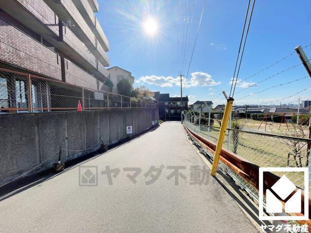 くずはパークハイツ　中古マンションのその他|前道はゆとりの広さで空き地もあり広々とした印象です。