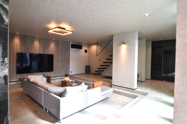 ソトに閉じて、ウチに開く。本物を知るあなただけにの居間・リビング|ゆとりあるリビングスペース。壁付けの大きなＴＶでゆっくりお寛ぎください。
