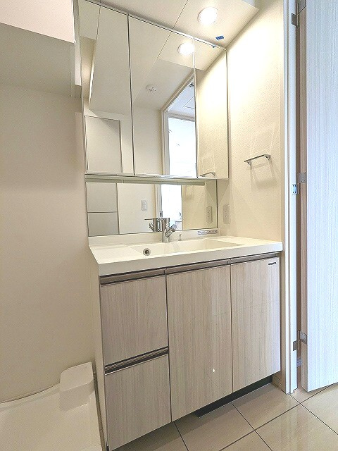 Urbanex KURAMAE RESIDENCEの洗面所|トイレと独立した3面鏡付、ハンドシャワー付独立洗面室、洗面台下にヘルスメーターストックあります、排水口のお手入れしやすく排水口を手前中央に配置した防水パン