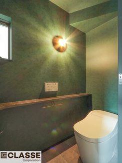 【トイレ】 | 城陽市平川長筬　一戸建 | 深いグリーンのクロスで統一し、
手洗いやカウンターを黒にして空間を引き締めました。