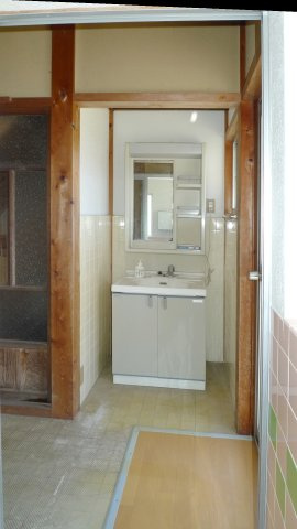 野郷町戸建ての洗面所|母家　１階。独立洗面台横に扉があり、玄関横に出入りできます。