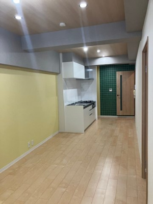 【居間・リビング】 | 進和江坂アーバンライフ | 空間がパッと明るくなるイエロー調のクロスと、表現豊かな木目が調和したリビング！ダウンライトを採用しています。