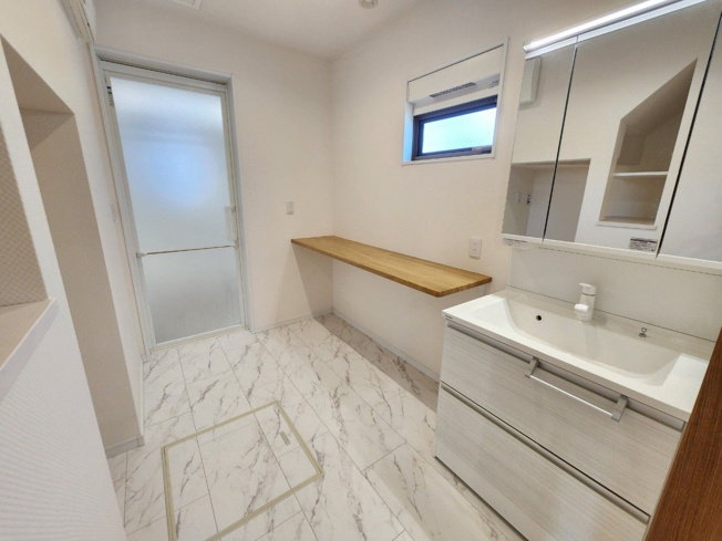 【独立洗面台】 | 宗像市田熊２丁目　戸建て | 収納力と機能性に優れた三面鏡洗面化粧台です。洗面台横には、身支度を整えたり洗濯物を片付けたりと様々な使い方ができそうな棚付きです