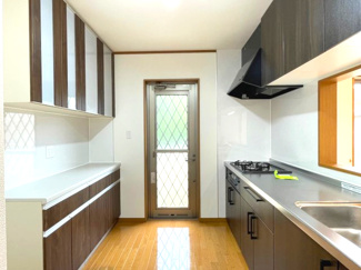 【キッチン】 | 木更津市真舟　中古戸建　木更津駅 | システムキッチン新品。対面キッチンでリビングの様子を見渡すことができます。
背面に大容量のカップボード設置で、調理器具をすっきり収納することができます。
庭に出たりゴミ出し等に便利な勝手口があります。