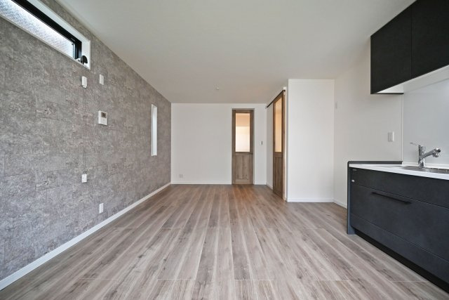 尼崎市東園田7丁目新築一戸建て│前面道路6ｍ+完成済の居間・リビング|1階LDKをダイニング側から撮影した内観写真です。高窓やアクセントクロス等デザイン性の高い設計に終始しています。