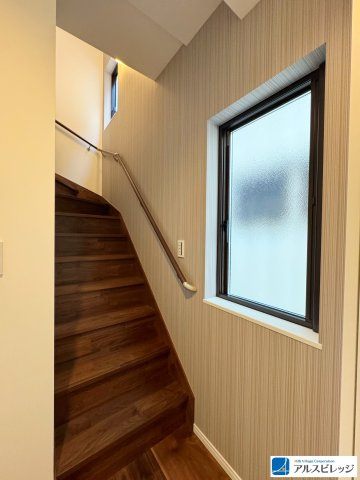 新築一戸建／ふじみ野市大井中央4丁目の玄関|毎日の上り下りを心地よく、美しく。ダークで落ち着いた縦柄のアクセントクロスが織りなす、ホテルのような上質空間。採光窓を確保し、デザイン性と安全性を両立した階段室です。