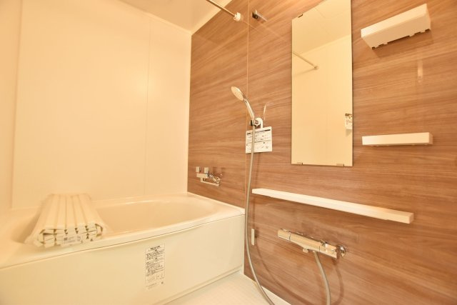 パラツィーナセシリア仁川弐番館の浴室|光沢のある木目調のパネルが特徴的なバスルームは、浴室乾燥機付きで、天候に左右されることなく洗濯物を干すことができます。