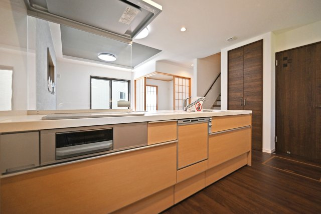 尼崎市東園田町2丁目新築一戸建て│4LDK+駐車2台（車種制限有）のキッチン|1階キッチン奥側から撮影した写真です。浄水器一体型水栓、食器洗い乾燥機などの充実した設備内容です。コンロ前は視界を確保した耐熱パネル使用。