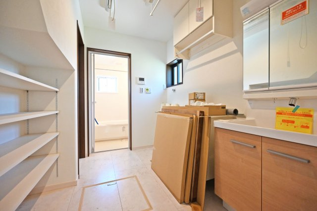 尼崎市東園田町2丁目新築一戸建て│4LDK+駐車2台（車種制限有）の洗面所|1階洗面室に入ってすぐの内観写真です。洗面台は3面鏡裏収納付きのドレッサーを採用しています。可動リネン棚も設けられており、高さを調整してタオル類から洗剤やストック用品まで収納可能。