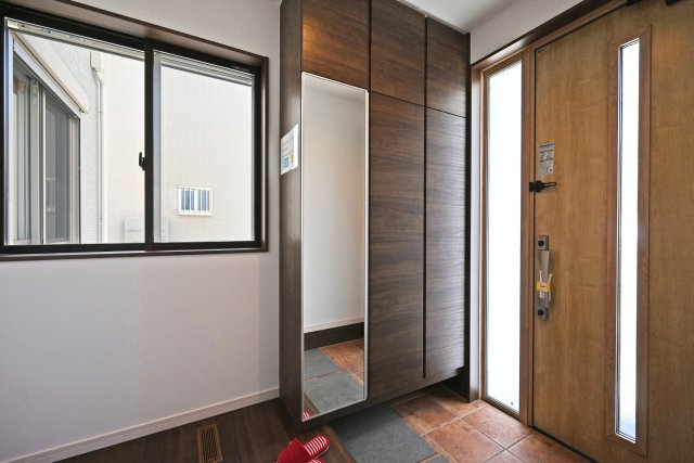 尼崎市東園田町2丁目新築一戸建て│4LDK+駐車2台（車種制限有）の玄関|1階玄関をホール側から撮影した内観写真です。 シンプルな玄関扉にシューズボックス、小窓を配置したオーソドックスな玄関です。