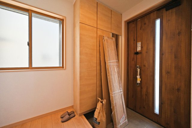 尼崎市東園田町2丁目新築一戸建て│2SLDK+駐車2台（車種制限有）の玄関|1階玄関をホール側から撮影した内観写真です。 シンプルな玄関扉にシューズボックス、小窓を配置したオーソドックスな玄関です。