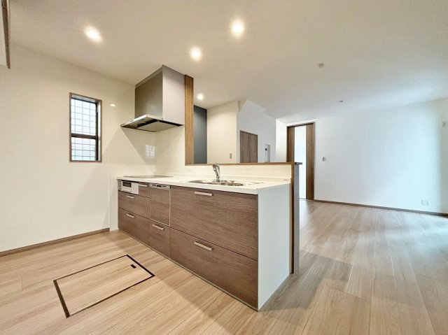 サニーサイド寺本1丁目新築戸建│3LDK+駐車駐輪可（車種制限有）のキッチン|1階LDKをキッチン越しに撮影した現地内観写真です。 広くて使いやすいキッチンは上部にダウンライトを採用しており、 オシャレな空間に仕上がりました。