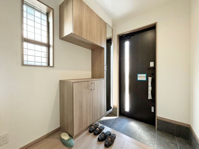 サニーサイド寺本1丁目新築戸建│3LDK+駐車駐輪可（車種制限有）の玄関|1階玄関を廊下側から撮影した内観写真です。 小窓を採用することで光が床面まで伸びる美しい空間に仕上がっています。