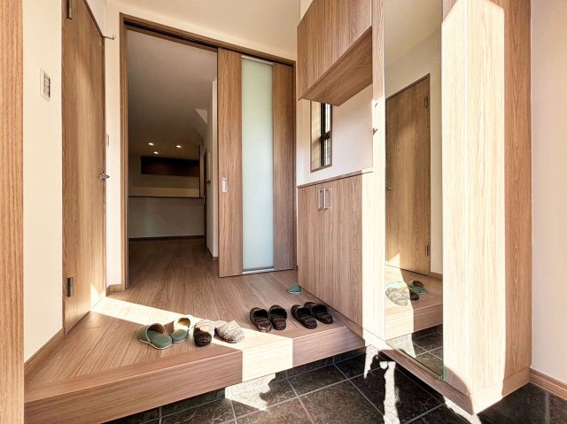 サニーサイド寺本1丁目新築戸建│3LDK+駐車駐輪可（車種制限有）の玄関|1階玄関に入ってすぐの内観写真です。グレーの土間タイルとのコントラストが利いた1棟の顔に相応しい空間です。右側にシューズボックスが配置されています。 