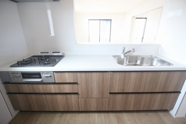 グラファーレ　小山市犬塚4丁目 2期　2号棟のキッチン|木目調のシステムキッチンは収納豊富。リビングを見渡せる設計で、家事をしながら家族との会話も楽しめます。