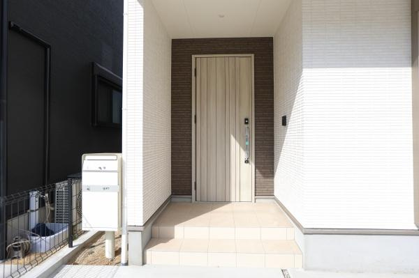 AG-HOUSE　上田町　B棟の玄関|玄関部分は屋根付きで天候に左右されにくい造りです。シンプルなデザインの玄関ドアが特徴的です。門柱とポストが使いやすい位置に設置されています。段差部分も広めで出入りしやすい印象があります。