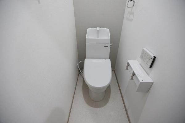 AG-HOUSE　上田町　B棟のトイレ|シンプルで白を基調としたトイレ空間です。壁付けのリモコンや手洗い付きタンクが設置されています。空間に無駄がなくすっきりとした印象を与えます。手に取りやすい位置にペーパーホルダーも配置されています。
