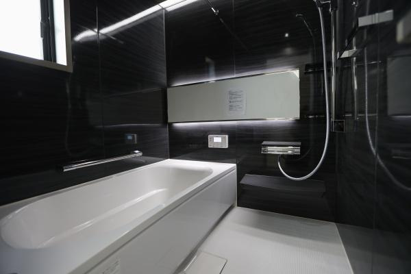 AG-HOUSE　光吉　A棟の浴室|ブラックの壁パネルが落ち着いた高級感を演出する浴室。ゆったり浸かれるバスタブに、浴室乾燥や追い焚き機能も搭載。窓付きで換気も良く、心身ともにリラックスできる癒しのバスタイムを叶えます♪