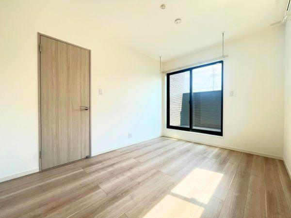 AG-HOUSE　光吉　A棟の洋室|大きな窓からたっぷりと光が差し込む明るい洋室。ナチュラルな木目調のフローリングと白壁が、清潔感と落ち着きを演出します。室内物干し付きで、天候に左右されず洗濯物が干せるのも嬉しいポイントです◎