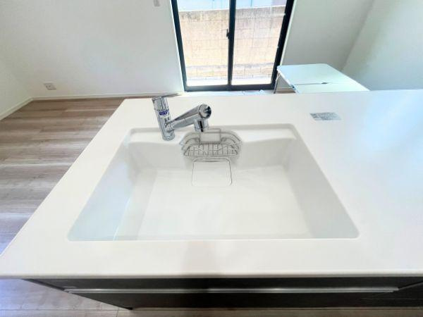 AG-HOUSE　光吉　A棟のキッチン|ゆとりのある広さで、大きな鍋やフライパンも洗いやすいワイドシンク。水ハネを抑えた設計と滑らかな一体型カウンターで、見た目もすっきり清潔感たっぷり。シャワー水栓付きで後片付けもラクラクです♪